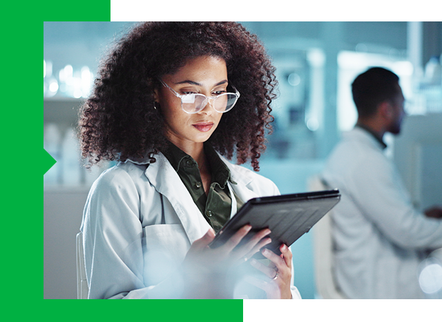 Scientist in lab coat examining tablet screen.