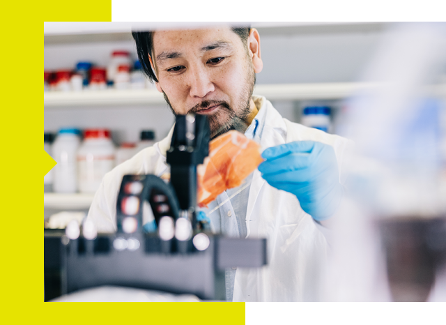 A scientist in a lab coat using a microscope.